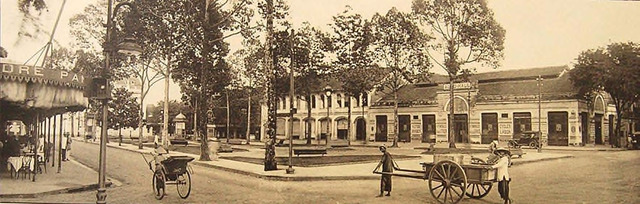 Fig. 30. Ludovic Crespin – Saigon at the start of the 1920s: Place de l’hôtel de ville, boulevard Bonnard, boulevard Charner. Municipal Hotel Plaza, corner of Bonnard (now Lệ Lợi) and Charner (now Nguyễn Huệ) Avenues. Right in the middle of Lệ Lợi is a public park with a statue of Francis Garnier facing the Municipal Theater. On the right is the shop “Auto-Hall,” which sold all kinds of automobiles. On the left is the establishment Pancrazi, which was open until the wee hours of the night. The cart-pullers on the right are staring in the direction of the photographer (Crespin).. 