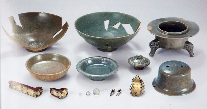 2. Burial goods excavated from the tomb of Queen Wŏndŏk (died 1239). Top row: two celadon bowls, a base for a celadon incense burner. Middle row: two celadon dishes, an inlaid celadon lid. Bottom row: two gilt-bronze coffin ornaments, three beads, two gilded pins, a gilded ornament, a celadon lid for a meibyŏng (prunus) vase. Meibyōng lid: 5.5 cm (h), 11 cm (diam.). National Museum of Korea. After Kungnip chungang pangmulgwan, Koryŏ wangsil ŭi tojagi (Seoul: T’ongch’ŏn munhwasa, 2008), p. 39 2. Burial goods excavated from the tomb of Queen Wŏndŏk (died 1239). Top row: two celadon bowls, a base for a celadon incense burner. Middle row: two celadon dishes, an inlaid celadon lid. Bottom row: two gilt-bronze coffin ornaments, three beads, two gilded pins, a gilded ornament, a celadon lid for a meibyŏng (prunus) vase. Meibyōng lid: 5.5 cm (h), 11 cm (diam.). National Museum of Korea. After Kungnip chungang pangmulgwan, Koryŏ wangsil ŭi tojagi (Seoul: T’ongch’ŏn munhwasa, 2008), p. 39