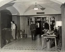 Group of men in East Quad entryway, some standing, two sitting at a table
