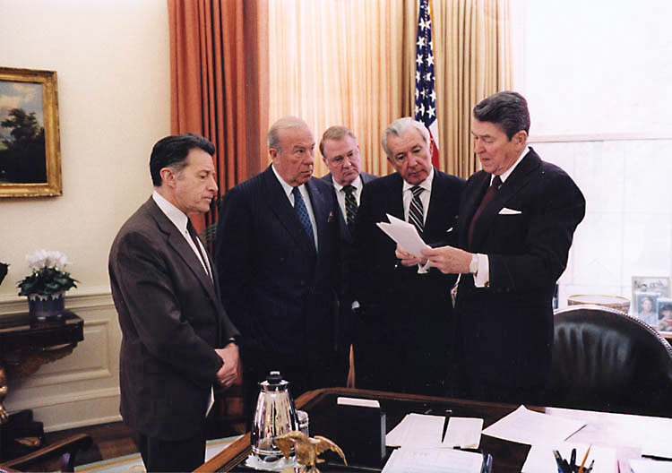 President Ronald Reagan with Secretary of Defense Caspar Weinberger, Secretary of State George Shultz, Attorney General Ed Meese, and Chief of Staff Don Regan discussing the President’s remarks on the Iran-Contra affair in the Oval Office, November 25, 1986. Photo by White House Photo Office via Wikimedia Commons. President Ronald Reagan with Secretary of Defense Caspar Weinberger, Secretary of State George Shultz, Attorney General Ed Meese, and Chief of Staff Don Regan discussing the President’s remarks on the Iran-Contra affair in the Oval Office, November 25, 1986. Photo by White House Photo Office via Wikimedia Commons.