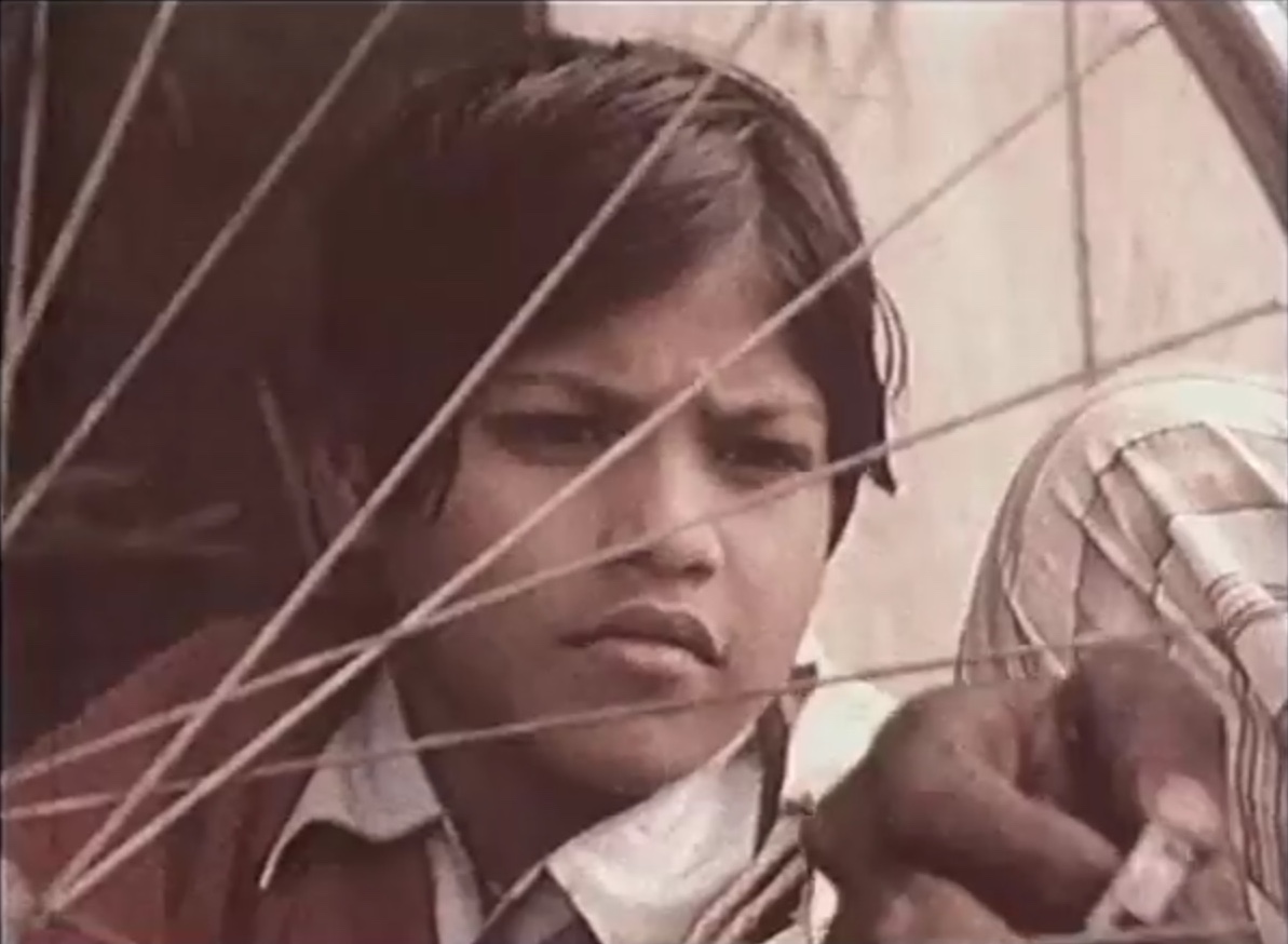 In a still from the educational film Kishan and His Magic Chariot(1980), produced by film educator and historian Vijaya Mulay, the title character observes the motion of a spinning wheel. In a still from the educational film Kishan and His Magic Chariot(1980), produced by film educator and historian Vijaya Mulay, the title character observes the motion of a spinning wheel.