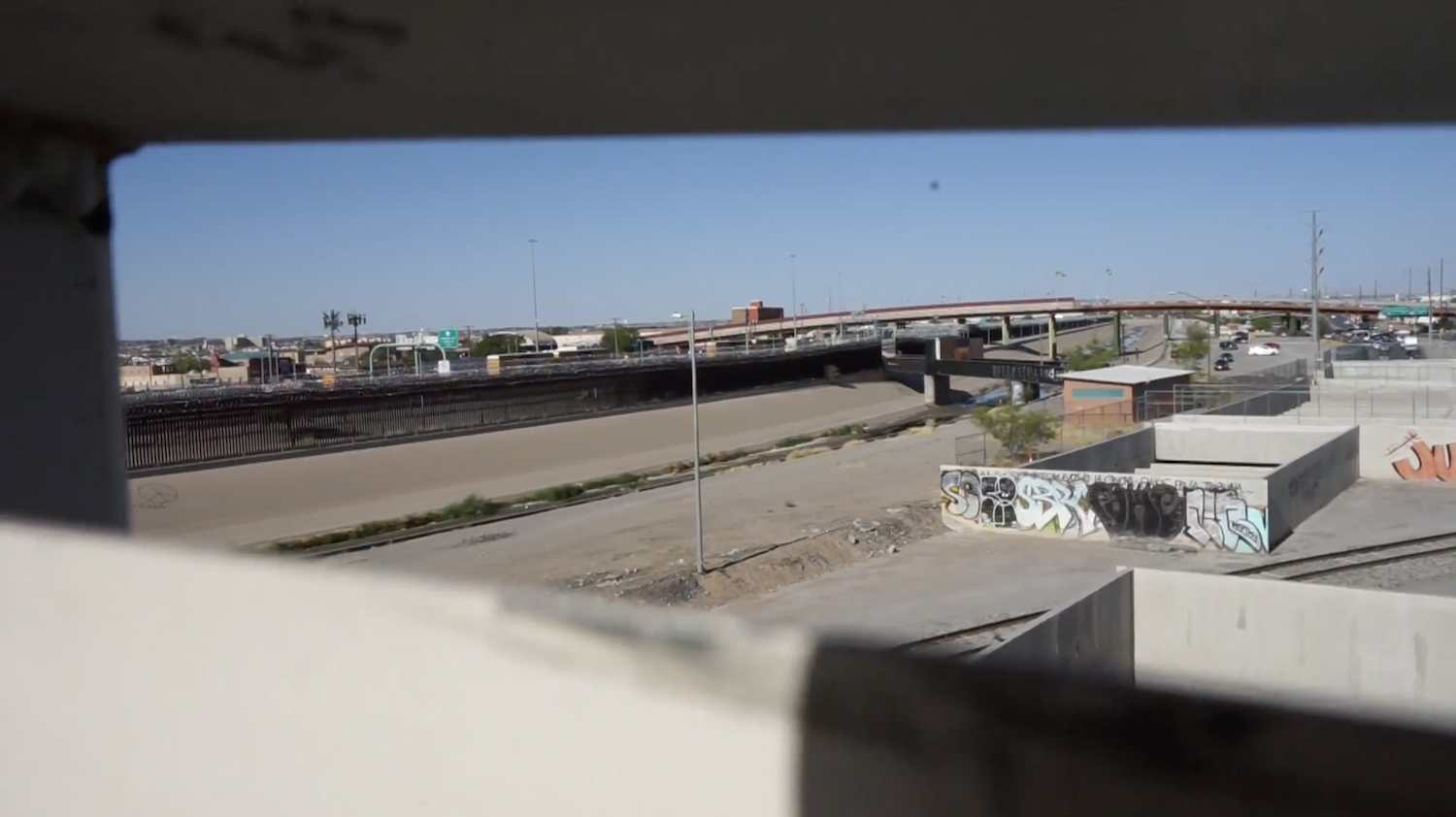 Figure 6. Screenshot of a point-of-view shot on a pedestrian bridge on the Mexico side of the El Paso-Juarez border that artfully vignettes the channeled Rio Bravo/Rio Grande in “The Border” (Dir. Kimberly Chavez). Figure 6. Screenshot of a point-of-view shot on a pedestrian bridge on the Mexico side of the El Paso-Juarez border that artfully vignettes the channeled Rio Bravo/Rio Grande in “The Border” (Dir. Kimberly Chavez).