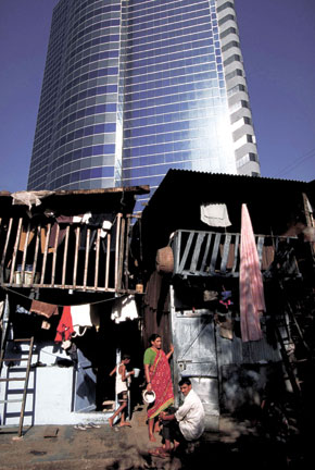 A modern high-rise building looms behind slum residents outside their home in India. ROBERT NICKELSBERG/Time Life Pictures/Getty Images A modern high-rise building looms behind slum residents outside their home in India. ROBERT NICKELSBERG/Time Life Pictures/Getty Images