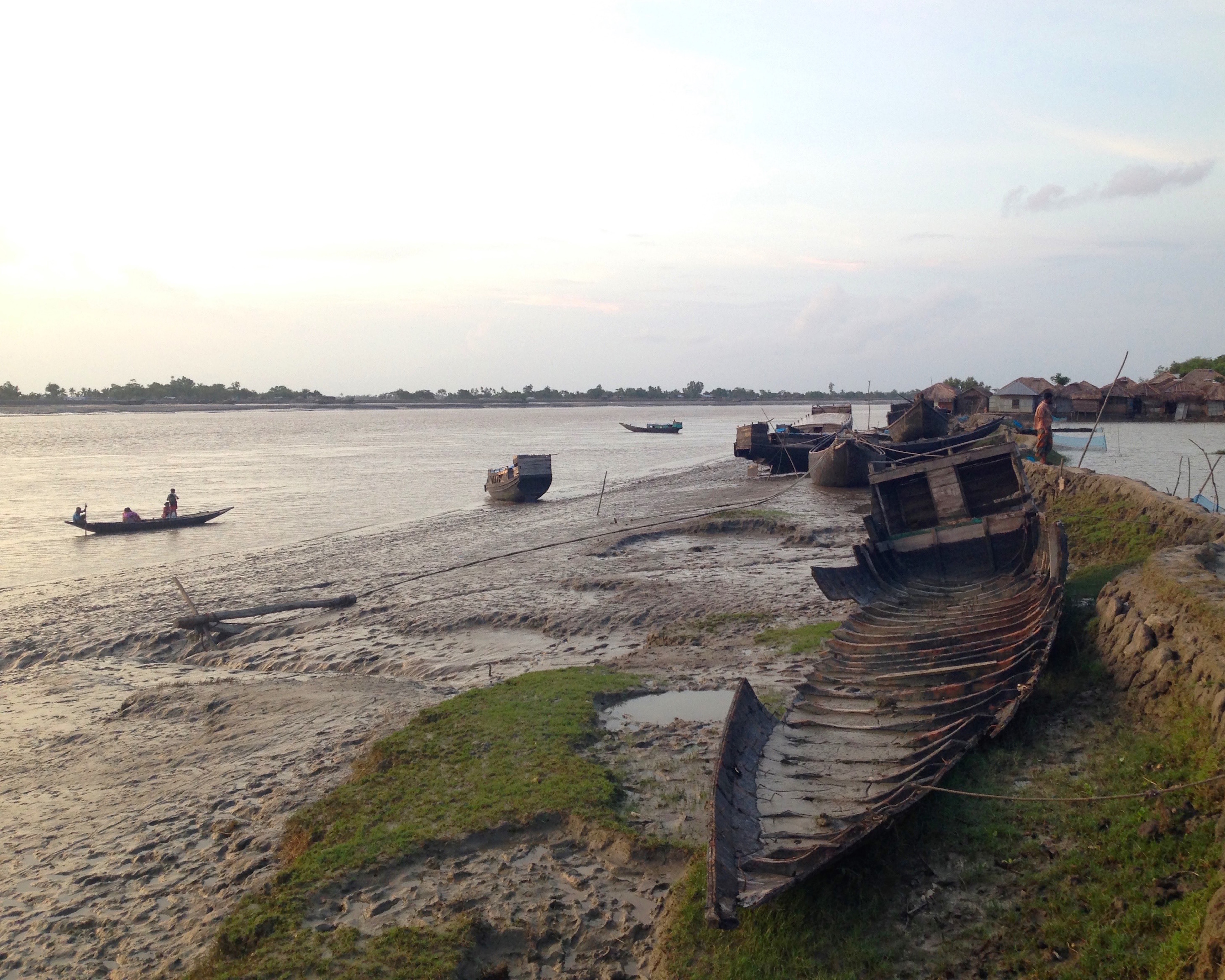 Figure 1. The shipwreck at low tide: A wrecked fishing boat awaits repair on a sliver of the upper bank of the Shipsha, a tidal river in southwest Bangladesh. Here, the waterways observe a schedule, expanding and contracting at high and low tide. The alluvial soil and riverine sediment that the river’s flow deposits downstream make the land in this part of East Bengal particularly fertile but also subject to increased ecological instability as banks are created and washed away. Figure 1. The shipwreck at low tide: A wrecked fishing boat awaits repair on a sliver of the upper bank of the Shipsha, a tidal river in southwest Bangladesh. Here, the waterways observe a schedule, expanding and contracting at high and low tide. The alluvial soil and riverine sediment that the river’s flow deposits downstream make the land in this part of East Bengal particularly fertile but also subject to increased ecological instability as banks are created and washed away.