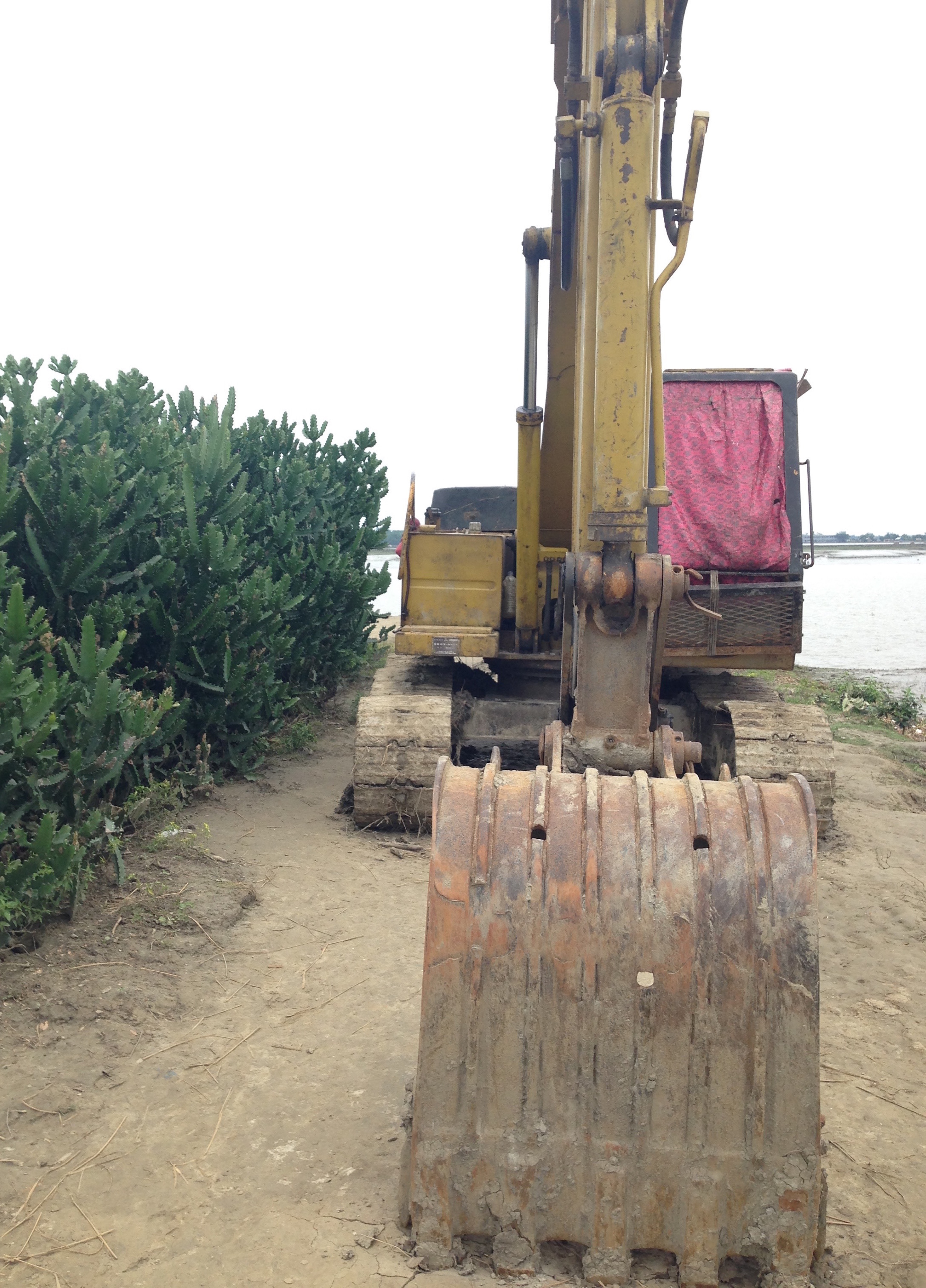 Figure 6. A backhoe idles at the top of the embankment: A temporary donation from a local contractor to help with some of the polder reconstruction, this backhoe can be used for major infrastructural work only when more of the floodwaters have receded. For now, it sits atop a stable part of the embankment. Figure 6. A backhoe idles at the top of the embankment: A temporary donation from a local contractor to help with some of the polder reconstruction, this backhoe can be used for major infrastructural work only when more of the floodwaters have receded. For now, it sits atop a stable part of the embankment.