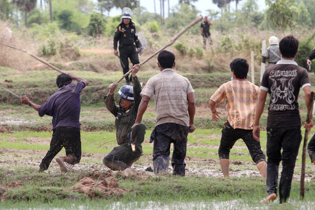Sovan Philong, ‘Violent Scenes in a Rice Paddy 08’, 2009. Digital C-Print. A villager and a police officer, both holding long sticks, ferociously smack each other while more villagers run in to give backup. Courtesy the artist and Asia Motion. Sovan Philong, ‘Violent Scenes in a Rice Paddy 08’, 2009. Digital C-Print. A villager and a police officer, both holding long sticks, ferociously smack each other while more villagers run in to give backup. Courtesy the artist and Asia Motion.