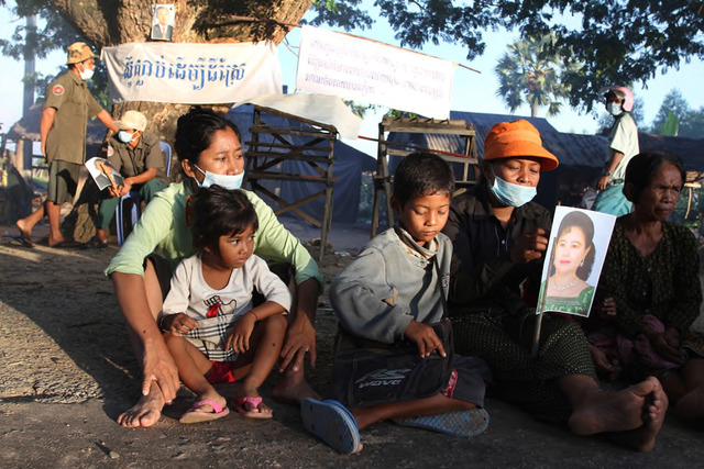 Sovan Philong, ‘Violent Scenes in a Rice Paddy 02’, 2009. Digital C-Print. Women and children holding a picture of the Cambodian Prime Minister’s wife, with a banner that reads ‘Die for farmland’ and a picture of the Prime Minister Hun Sen in the background. In desperation, the villagers appeal to the very government that ordered the police to raid them. Courtesy the artist and Asia Motion. Sovan Philong, ‘Violent Scenes in a Rice Paddy 02’, 2009. Digital C-Print. Women and children holding a picture of the Cambodian Prime Minister’s wife, with a banner that reads ‘Die for farmland’ and a picture of the Prime Minister Hun Sen in the background. In desperation, the villagers appeal to the very government that ordered the police to raid them. Courtesy the artist and Asia Motion.