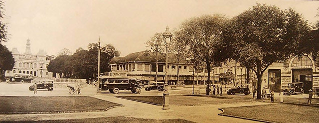 Fig. 31. Ludovic Crespin – Saigon at the start of the 1920s: Rond point entre le boulevard Charner et le boulevard Bonnard. Rotary at Nguyễn Huệ (Charner) and Lệ Lợi (Bonnard) Avenues. In the middle of the rotary is a round platform where musicians played classical or military pieces evenings at 7 o’clock, for the entertainment of the French. The Vietnamese called this intersection “Bugler’s Intersection.” Note the tour bus in the center with the advertisement on top: coiffre-art – Le Gaulois. On the right is the “Auto-Hall,” and Pancrazi on the next street.. 